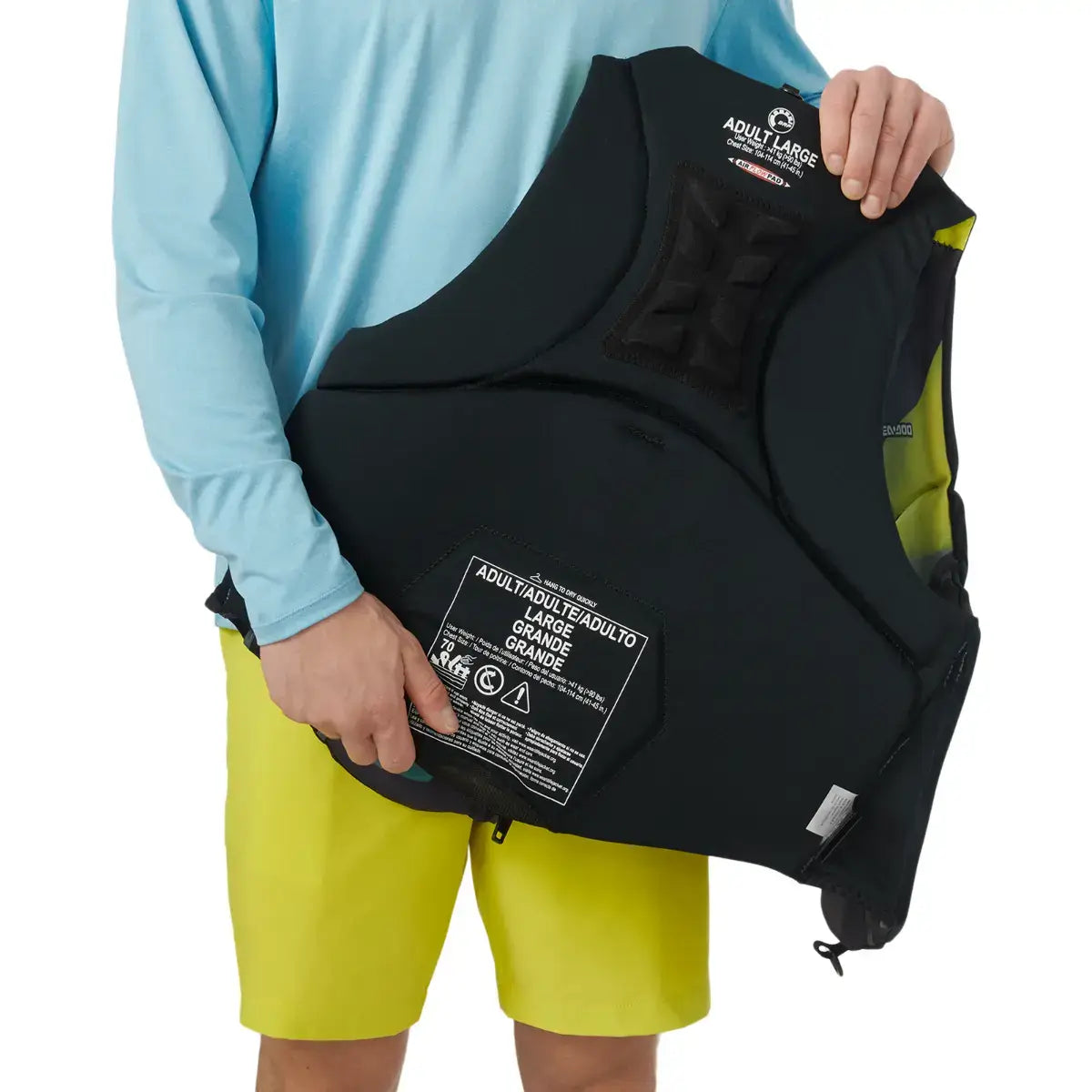 A person holding a Sea-Doo Airflow Sunset Edition Life Jacket, showcasing its design and labeling for adult size.
