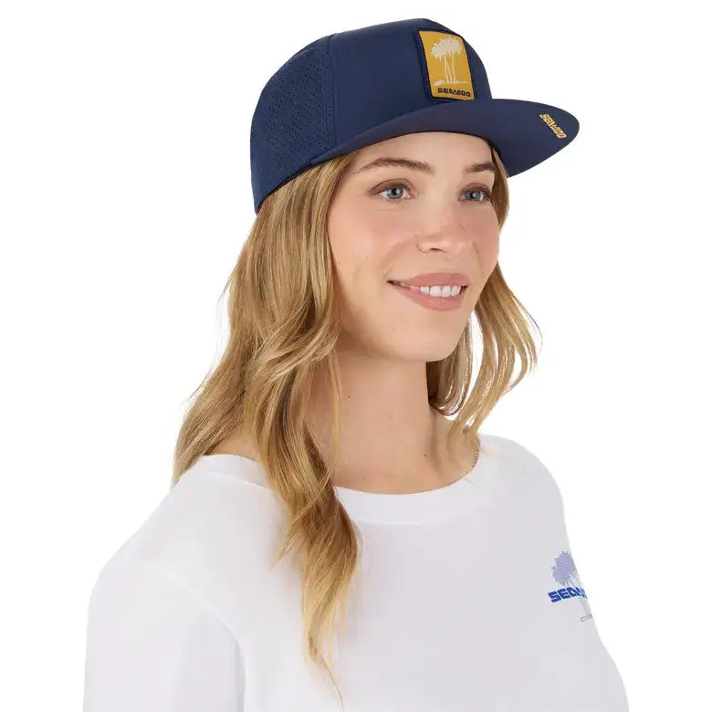 Woman wearing a Sea-Doo unisex laser cut mesh cap with palm tree design and logo.