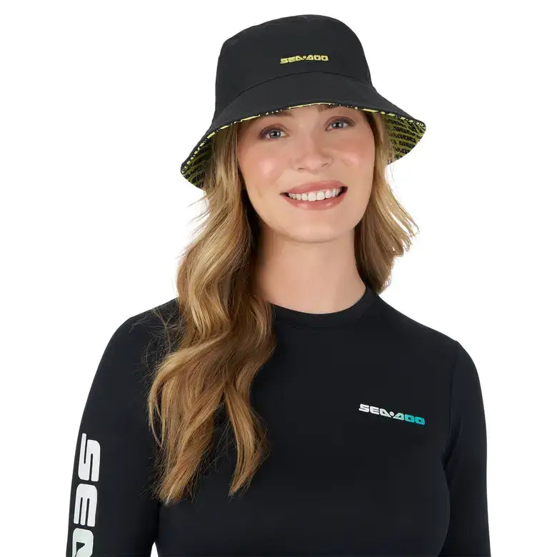 Girl wearing a Sea-Doo reversible bucket hat with UPF protection, smiling, black and green design, stylish sun protection.