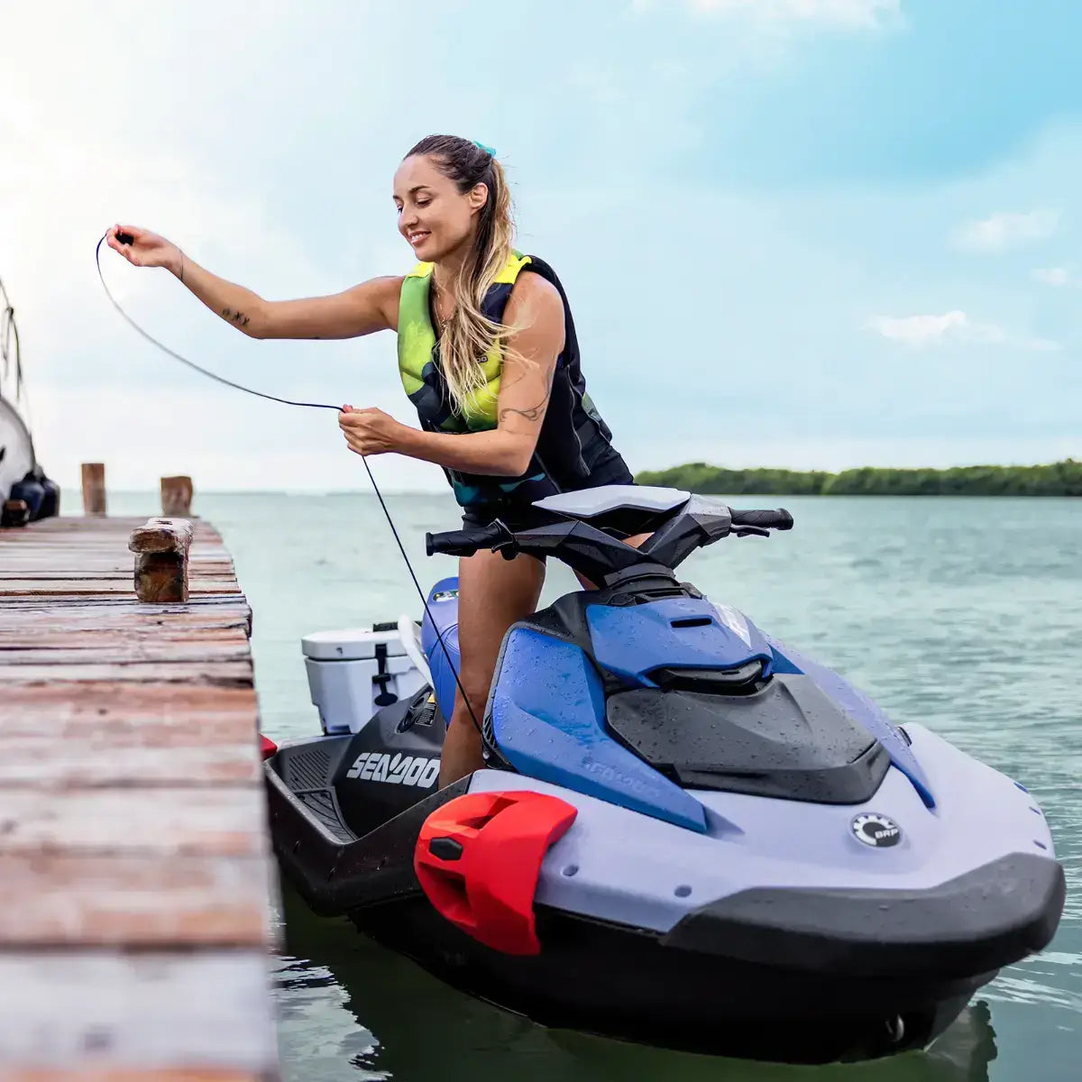 Woman on a Sea-Doo Spark by a dock with a scenic background