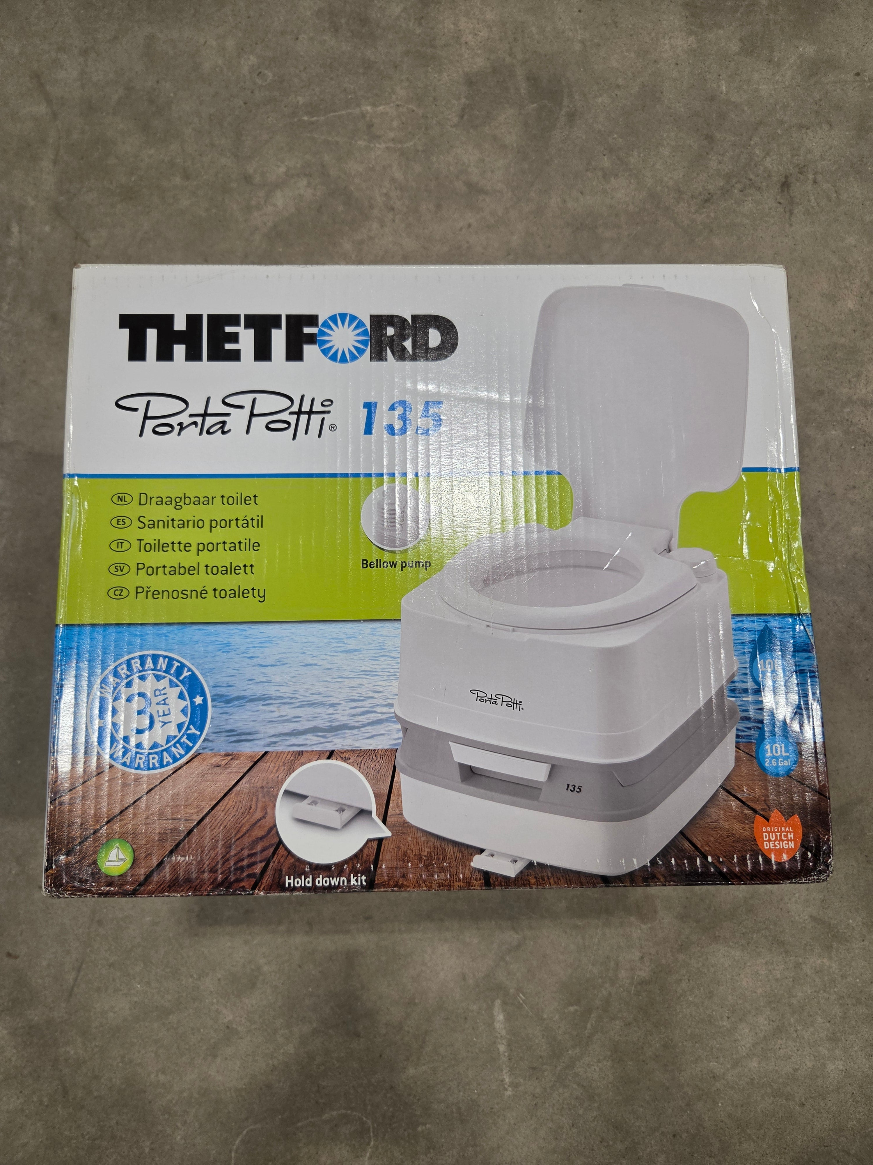 Thetford BritePath 13.5 portable toilet paper dispenser in its original retail packaging, placed on a gray concrete floor.