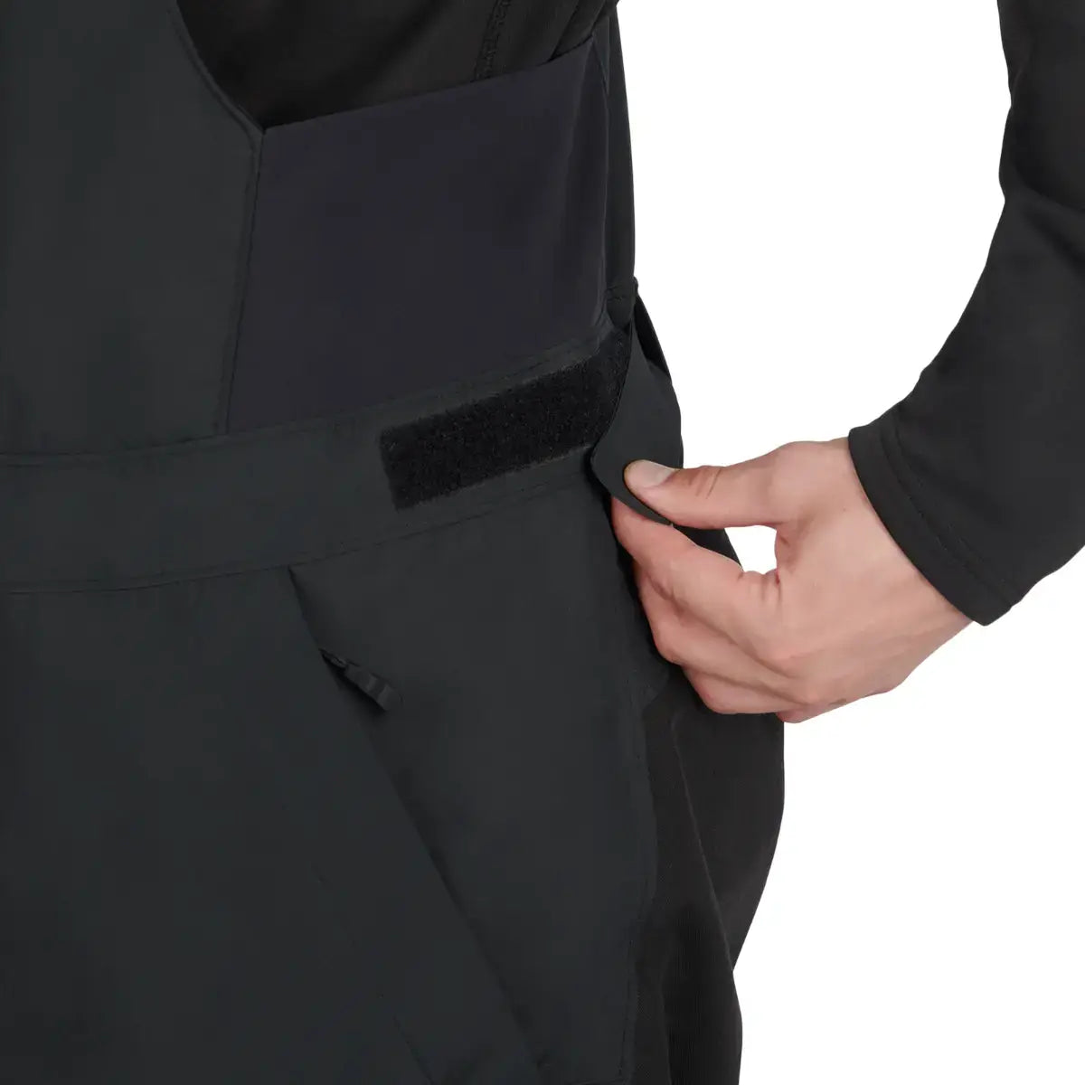 Close-up of a person wearing a black high pants with a hand adjusting straps on a white background