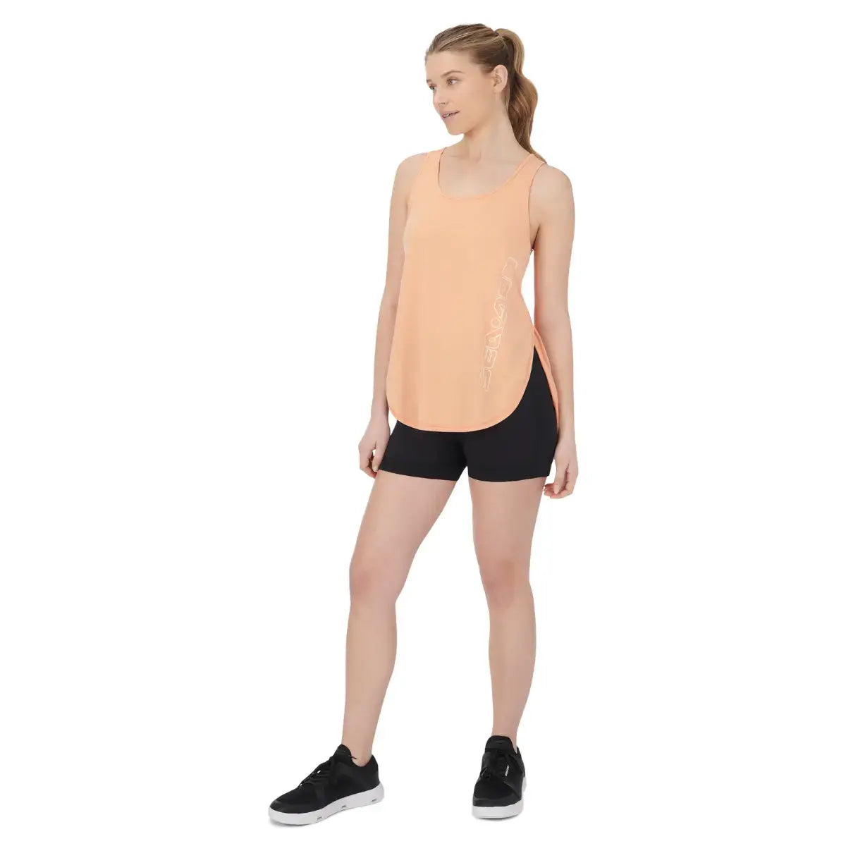 Sea-Doo women's racerback tank top in peach color, styled with black shorts and athletic shoes for active lifestyle.