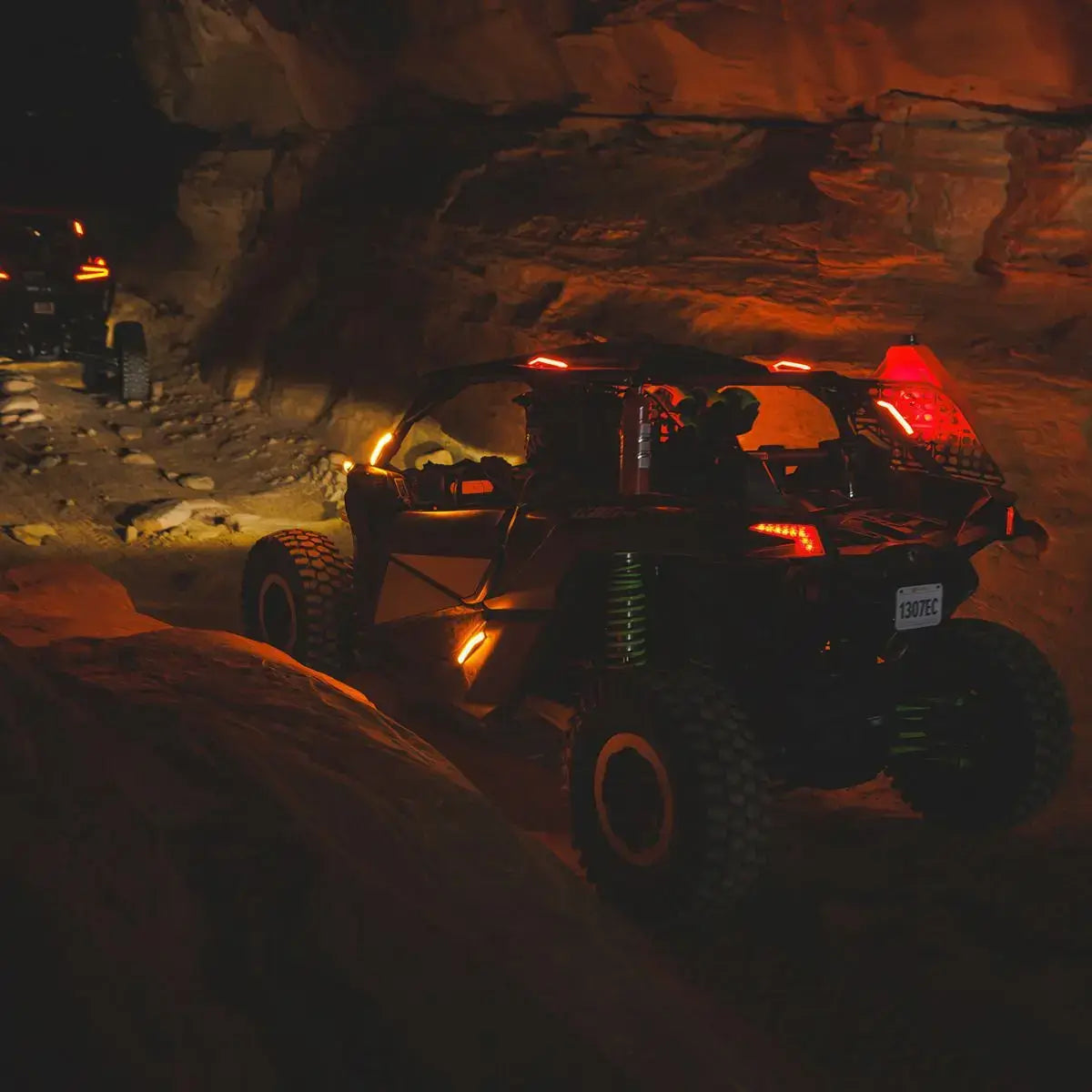 Off-road vehicle navigating a rocky cave entrance at night.
