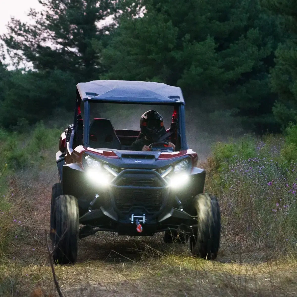Off-road vehicle driving through a forest with headlights on