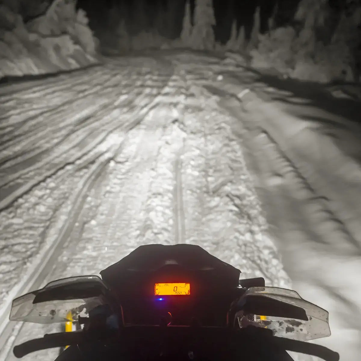 First-person view from a snowmobile on a snowy trail at night