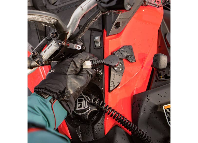Gloved rider connecting Ski-Doo E-LinQ accessory plug on red REV Gen4 snowmobile console, 860201719