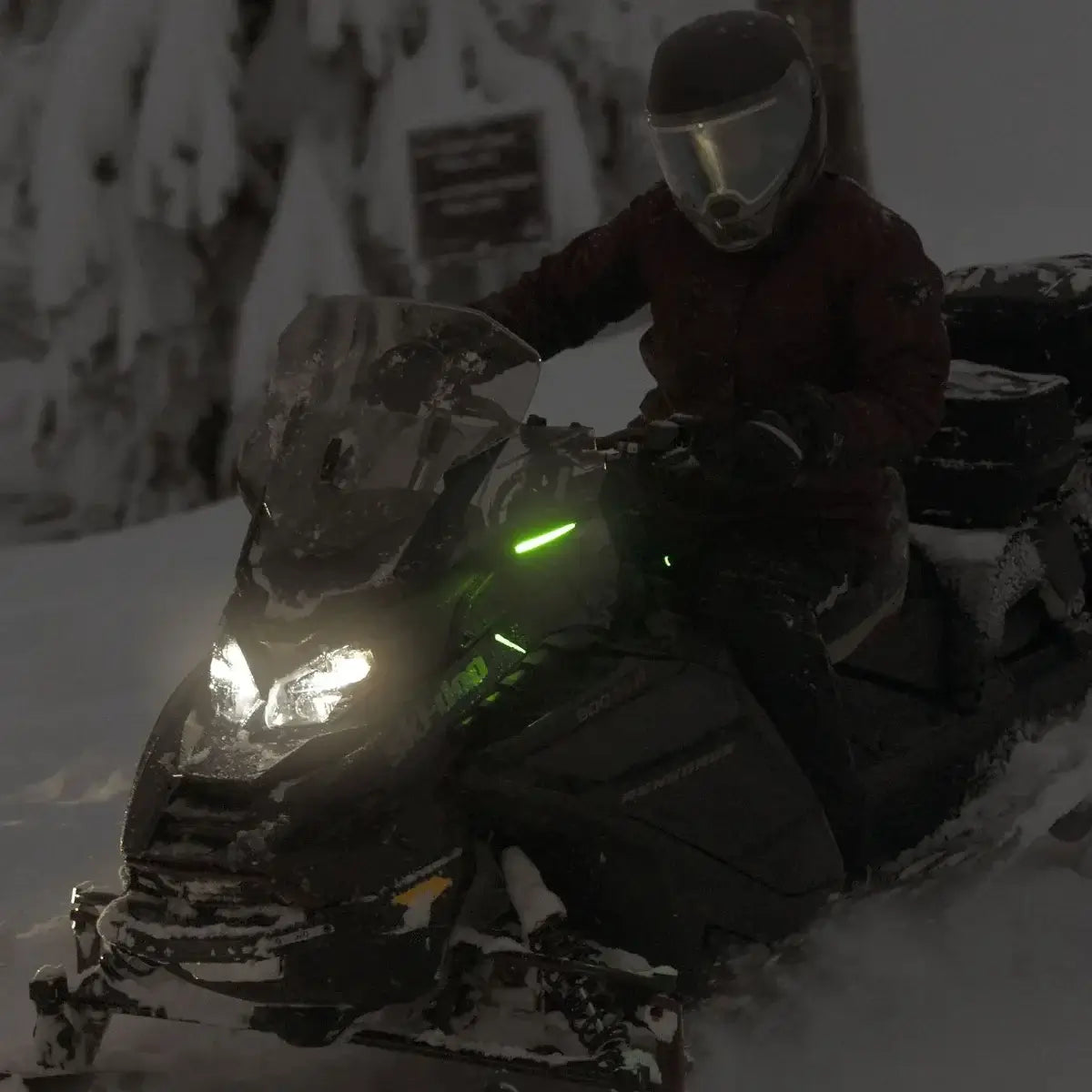Person on a snowmobile in a snowy landscape with trees in the background