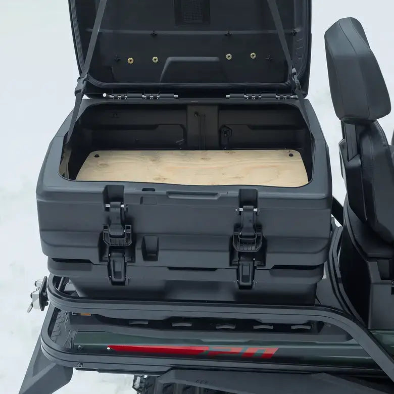 Open black storage compartment with a wooden board inside on a vehicle, on a light gray background