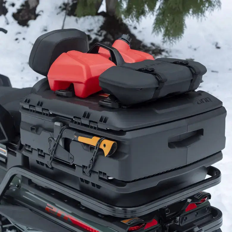 Black roof rack with red and black storage box on a vehicle in a snowy environment