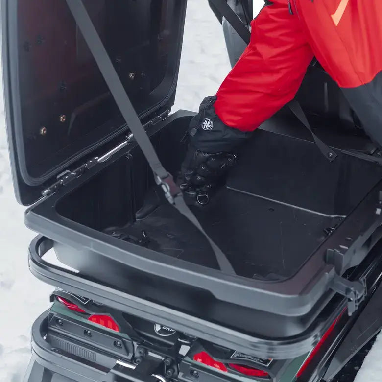 Person opening a black storage compartment on a vehicle in a snowy environment