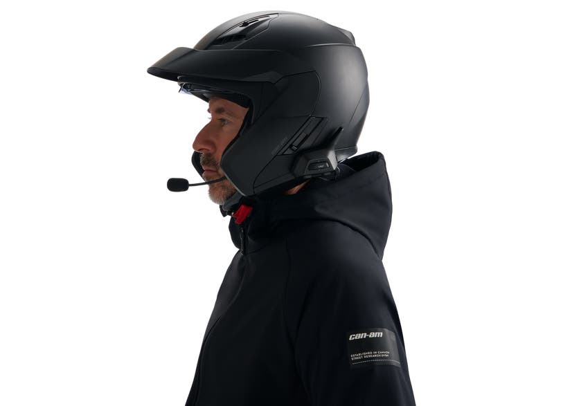 Rider wearing black open-face helmet with BRP Vibe Universal Comm System mounted, side view