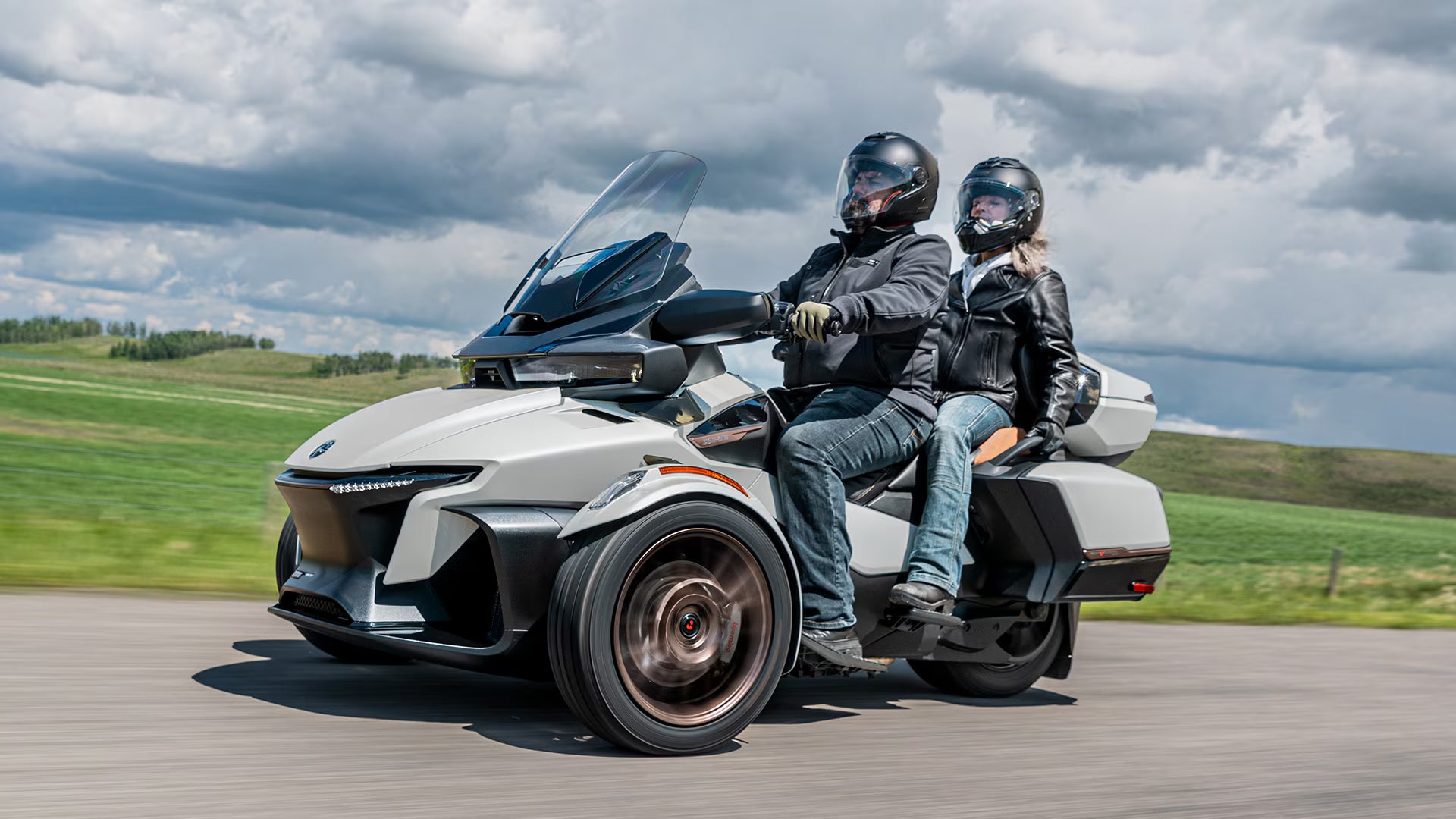 Two people riding a trike on a road with a scenic background