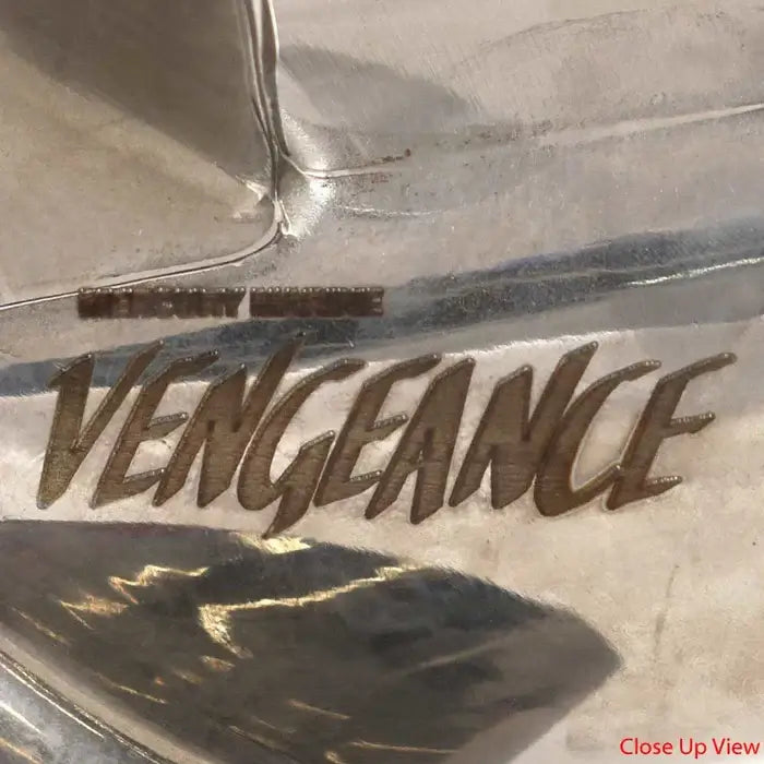Close-up of a metallic surface with 'VENGEANCE' engraved on it.