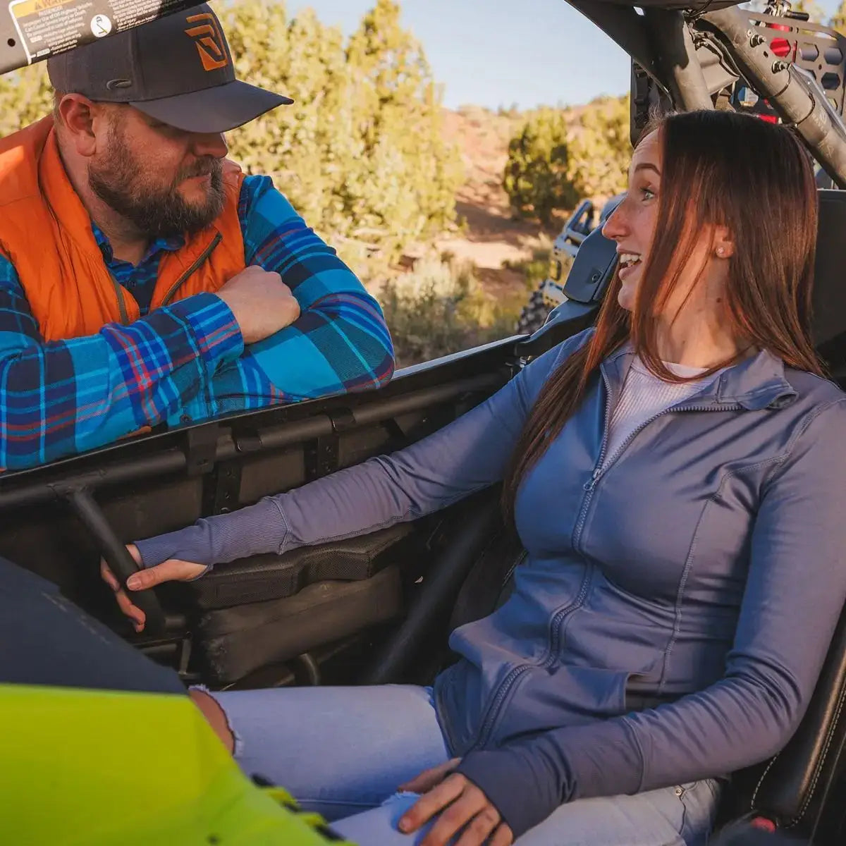 Two people sitting inside a vehicle with a scenic outdoor background