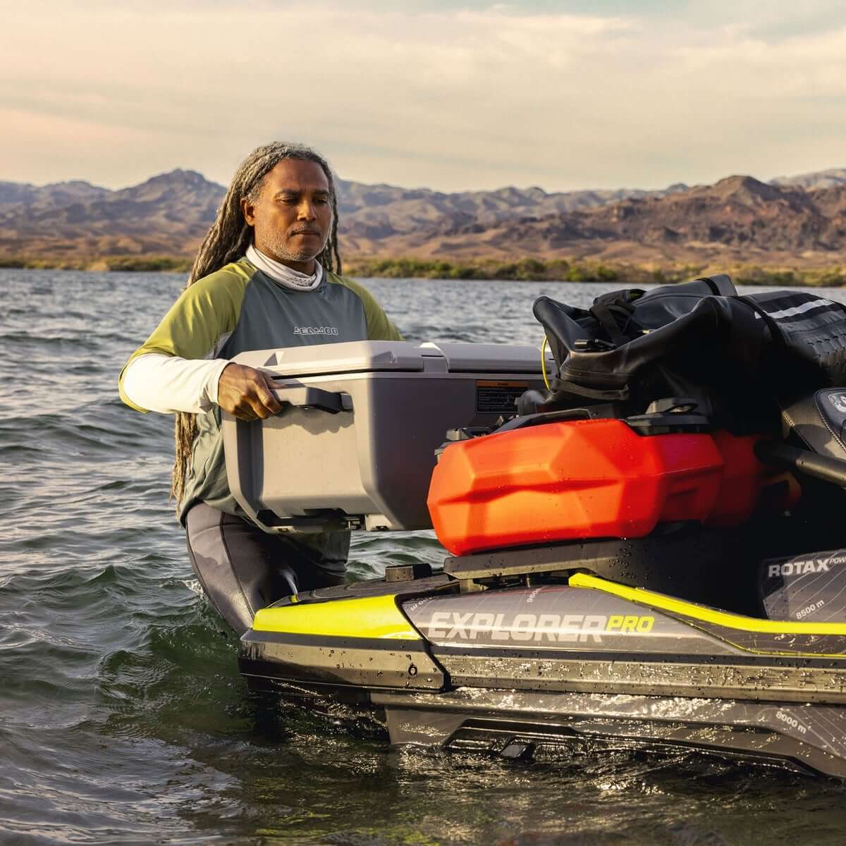 A woman standing in the water next to a jet ski