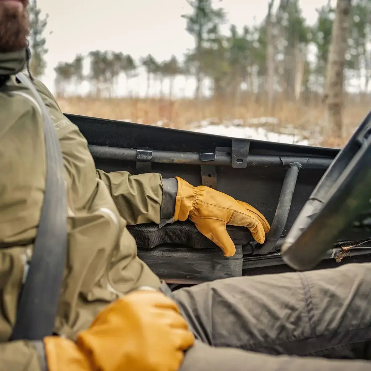 Person in outdoor setting, possibly in a forest or marsh, wearing gloves and a jacket.