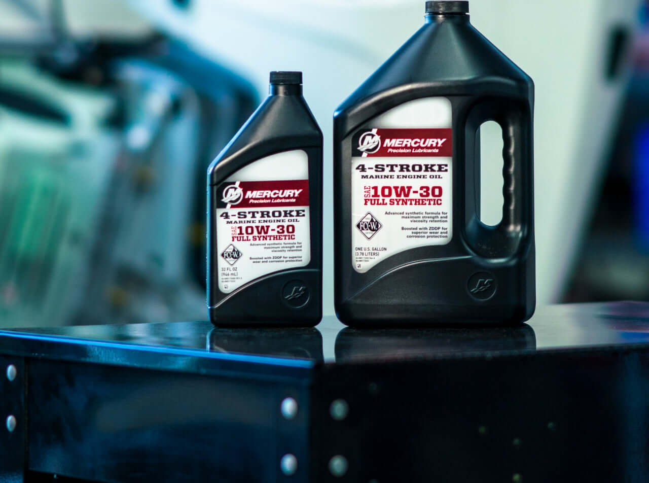 Two bottles of Mercury 4-Stroke engine oil on a reflective surface with a blurred background.