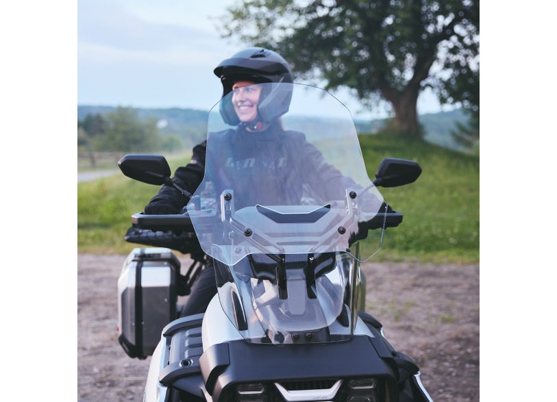 Rider on Can-Am Canyon three-wheeler with clear high windshield installed, front view outdoors