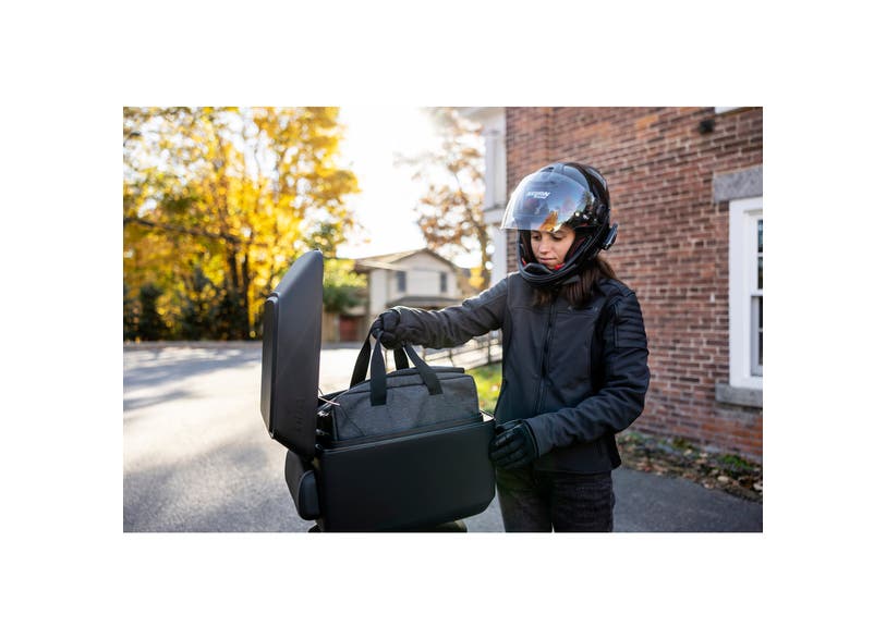 Rider placing gray inner liner bag into Can-Am Ryker LinQ top case