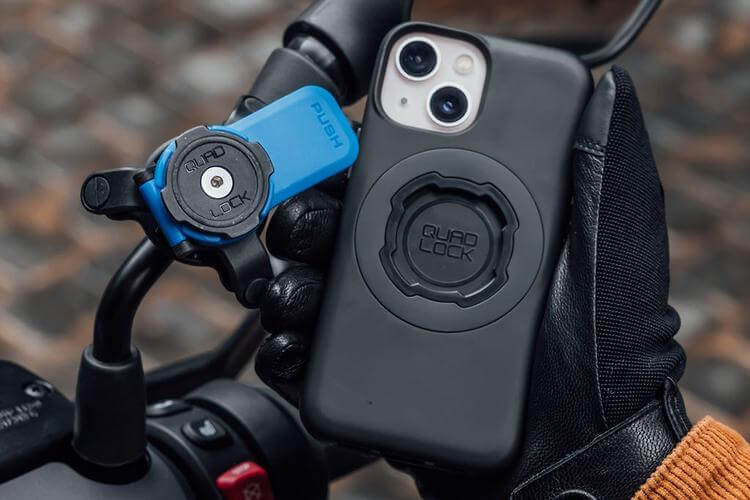 Phone case with 'Quad Lock' branding attached to a motorcycle handlebar.