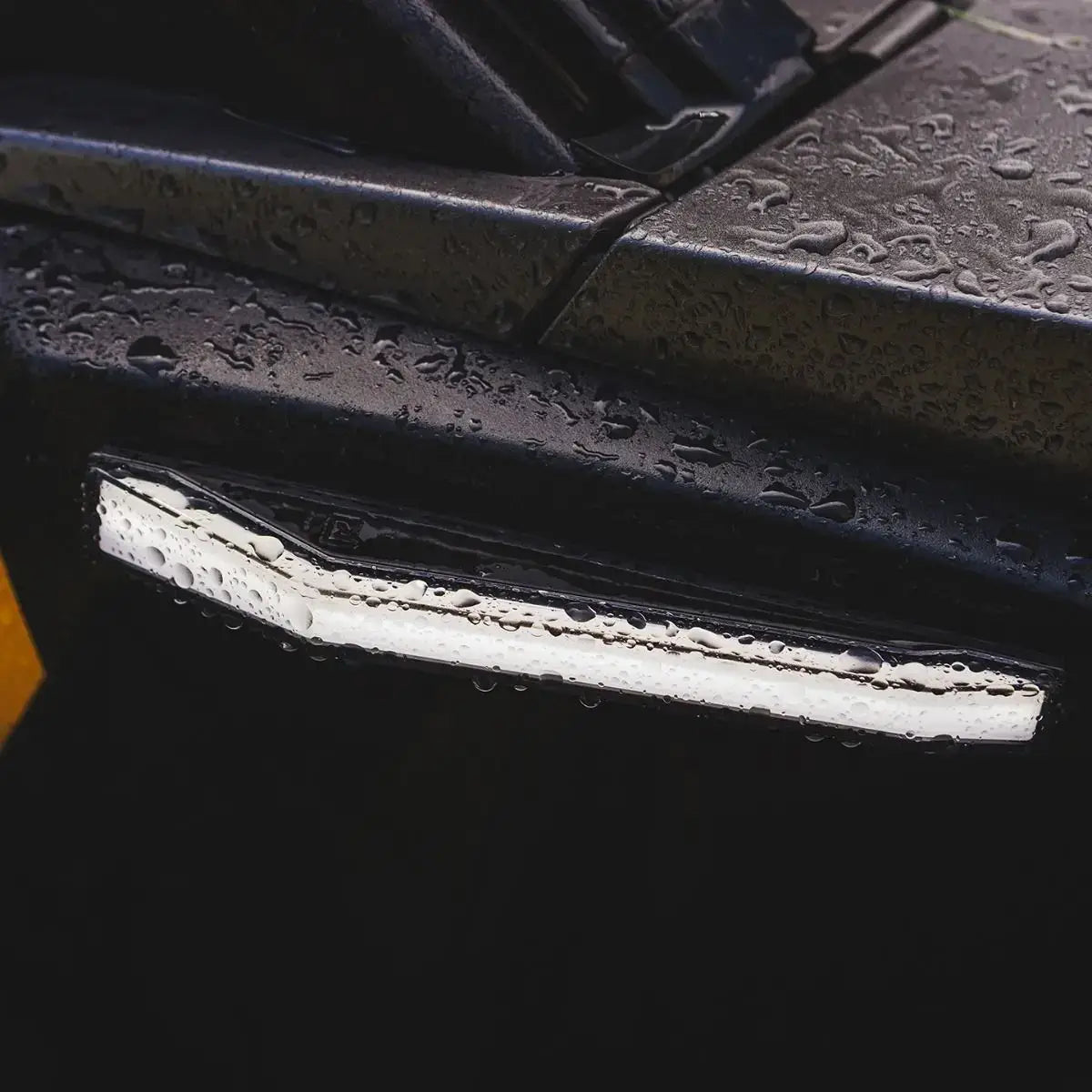 Close-up of a black grill with a white light strip on a dark background