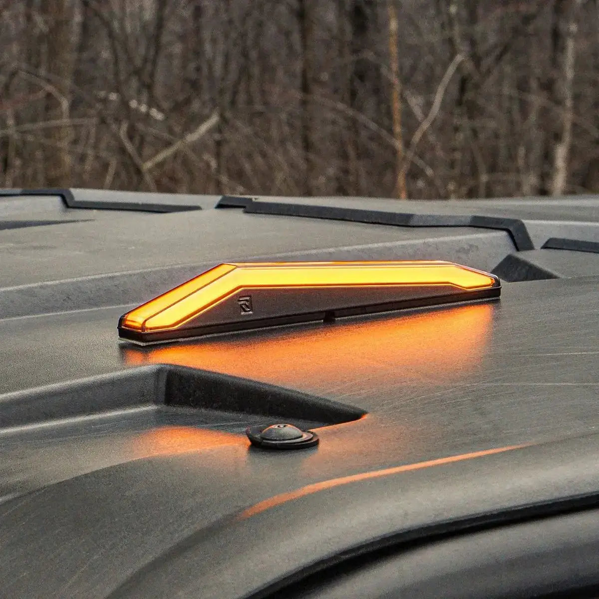 Orange LED light on a vehicle roof with a blurred natural background