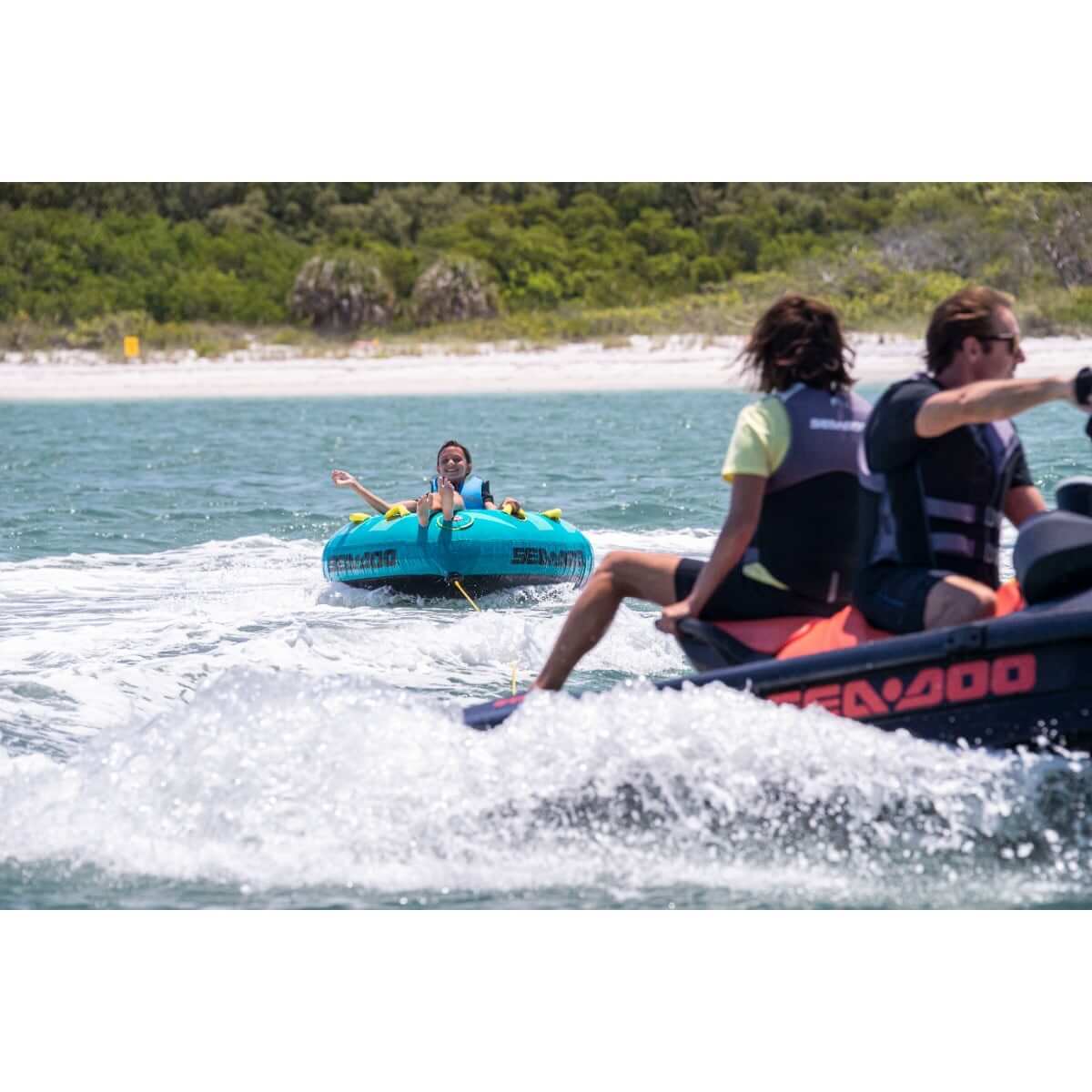 Sea-Doo 1-person triangle towable tube in teal, rider towed behind Sea-Doo watercraft on lake