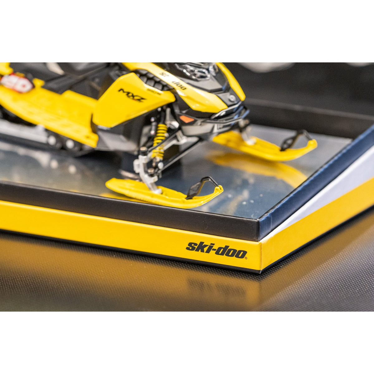 Yellow skis and front shocks of the Ski-Doo diecast on the mirrored base of the Ski-Doo box