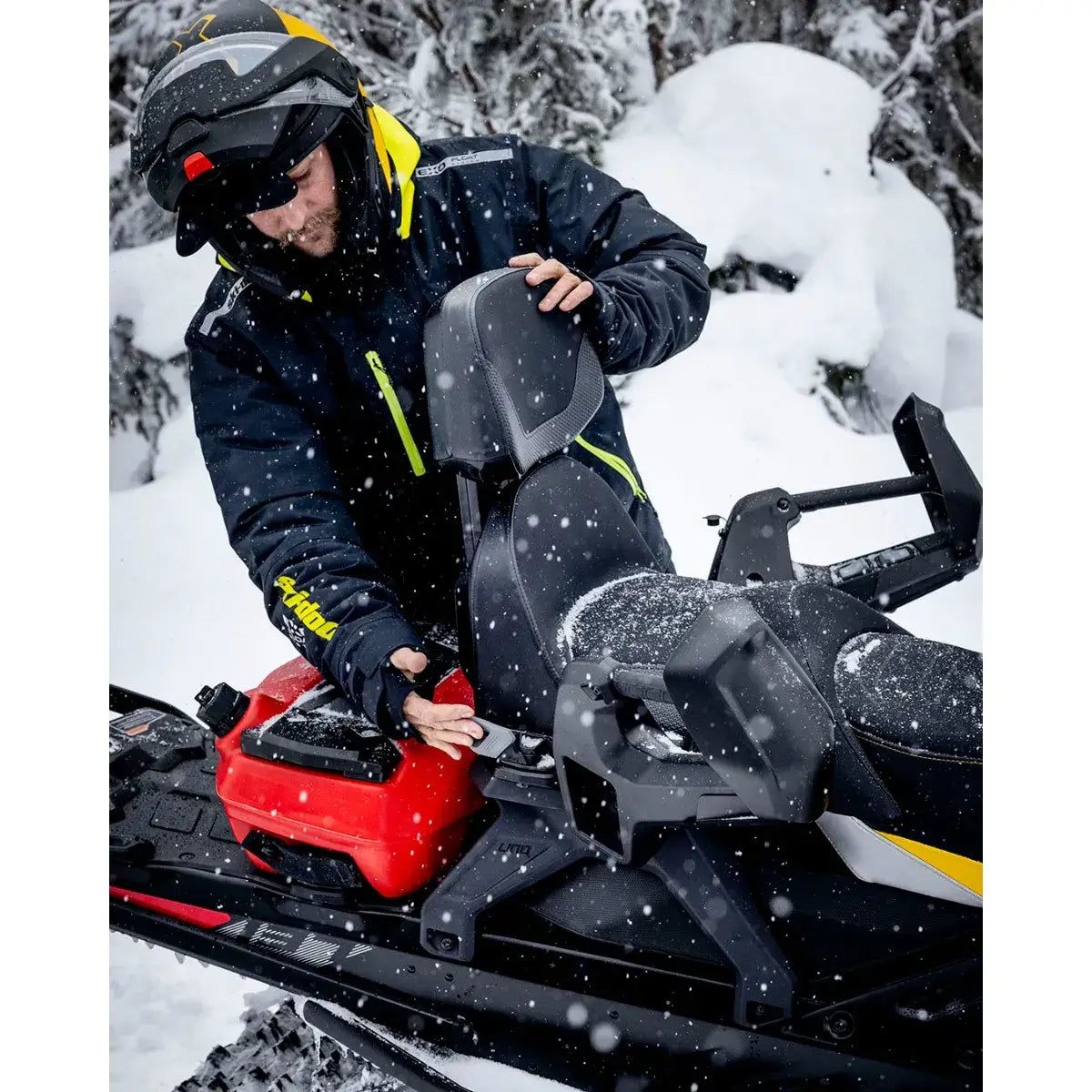 Person adjusting seat on Ski-Doo in snowy landscape