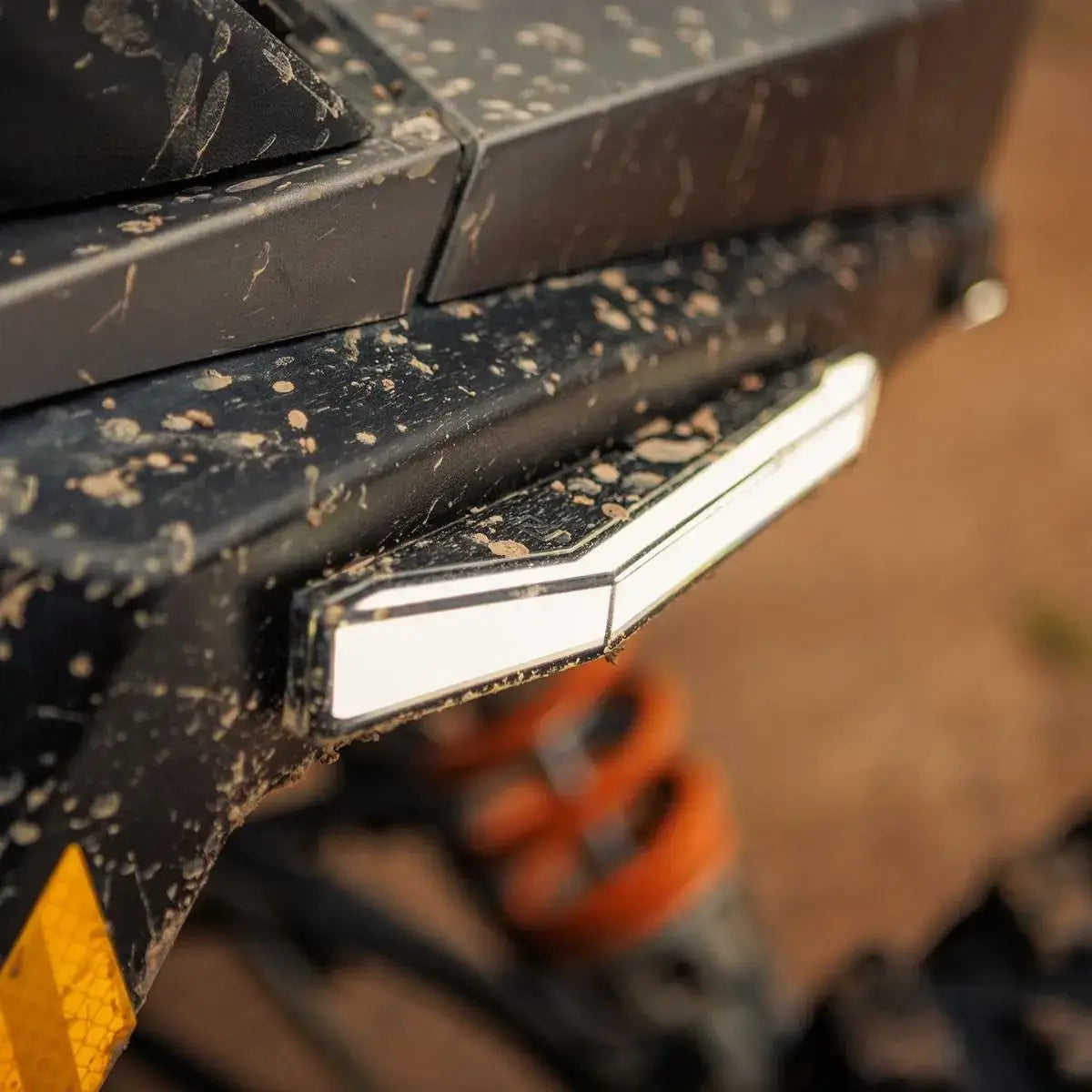 Close-up of a dirt-covered vehicle bumper with a light, blurred background