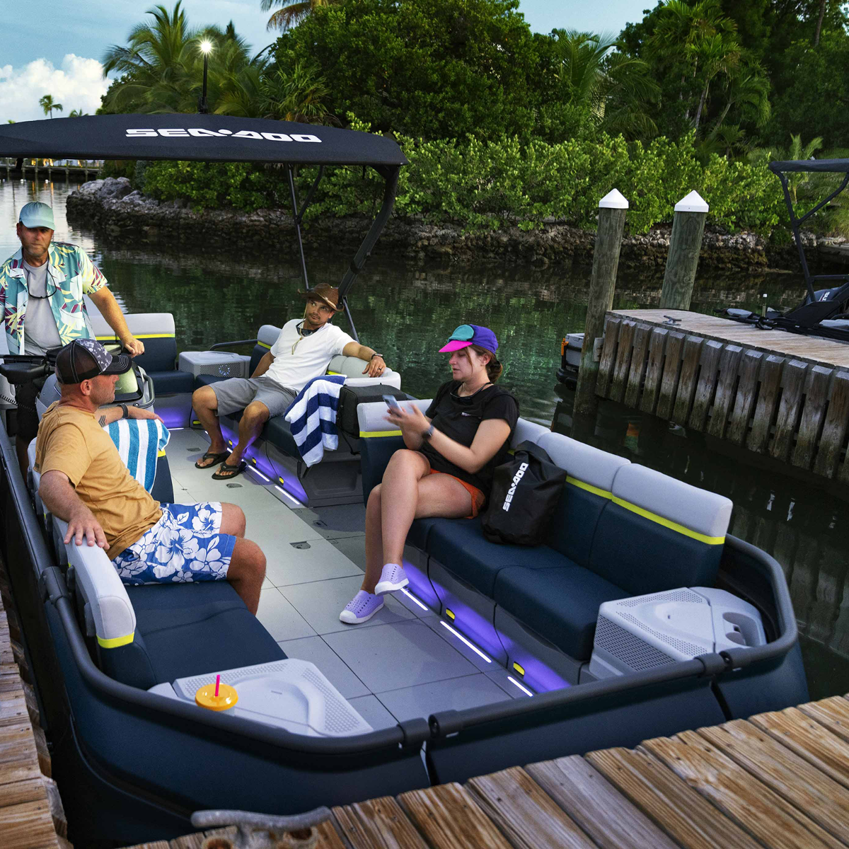 Passengers relaxing on a Sea-Doo Switch pontoon with the JL Audio system tables lit up
