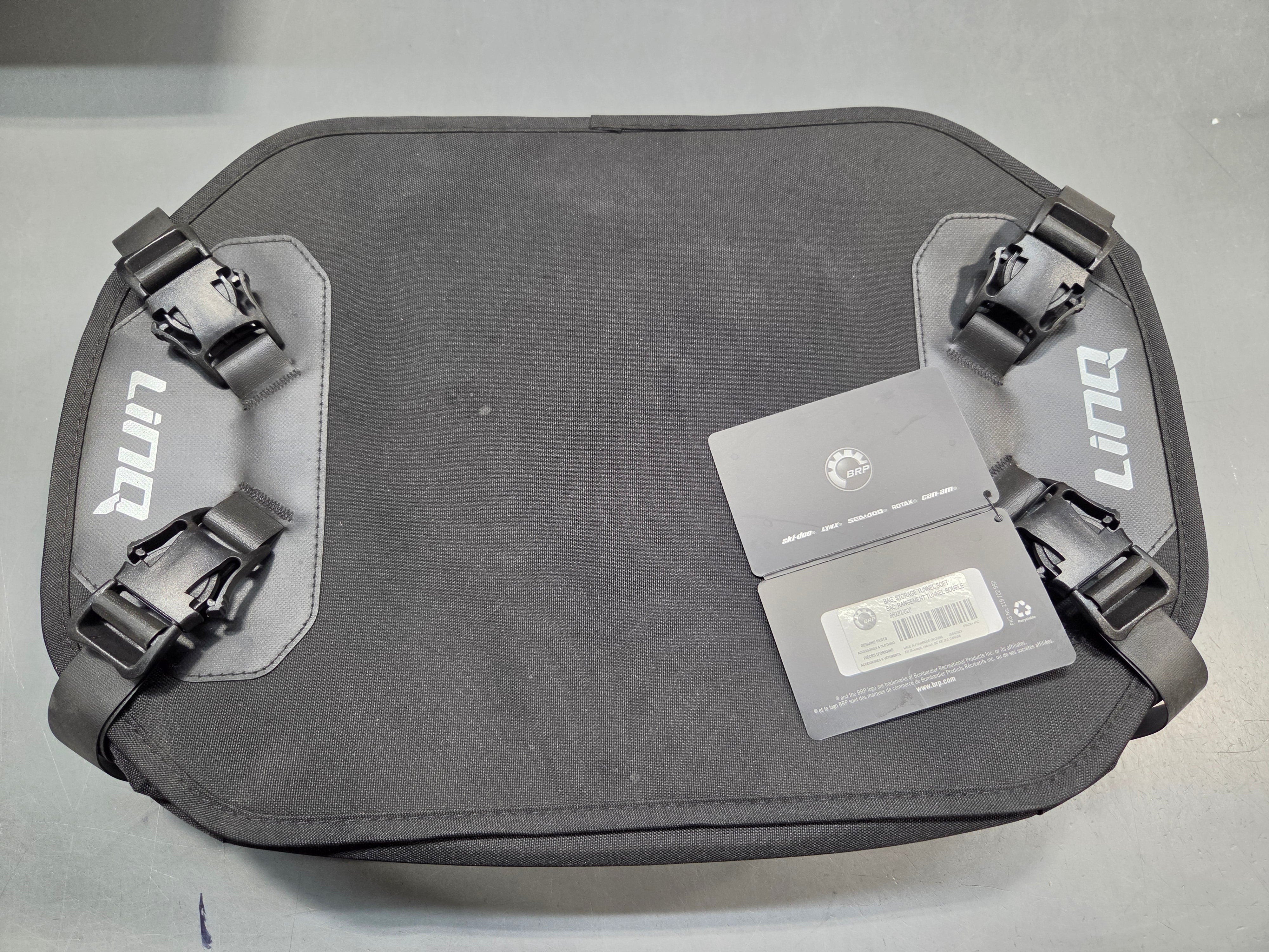 A dark gray Lingo bag with adjustable straps and a gray retail tag attached, photographed from a top-down angle on a gray surface.