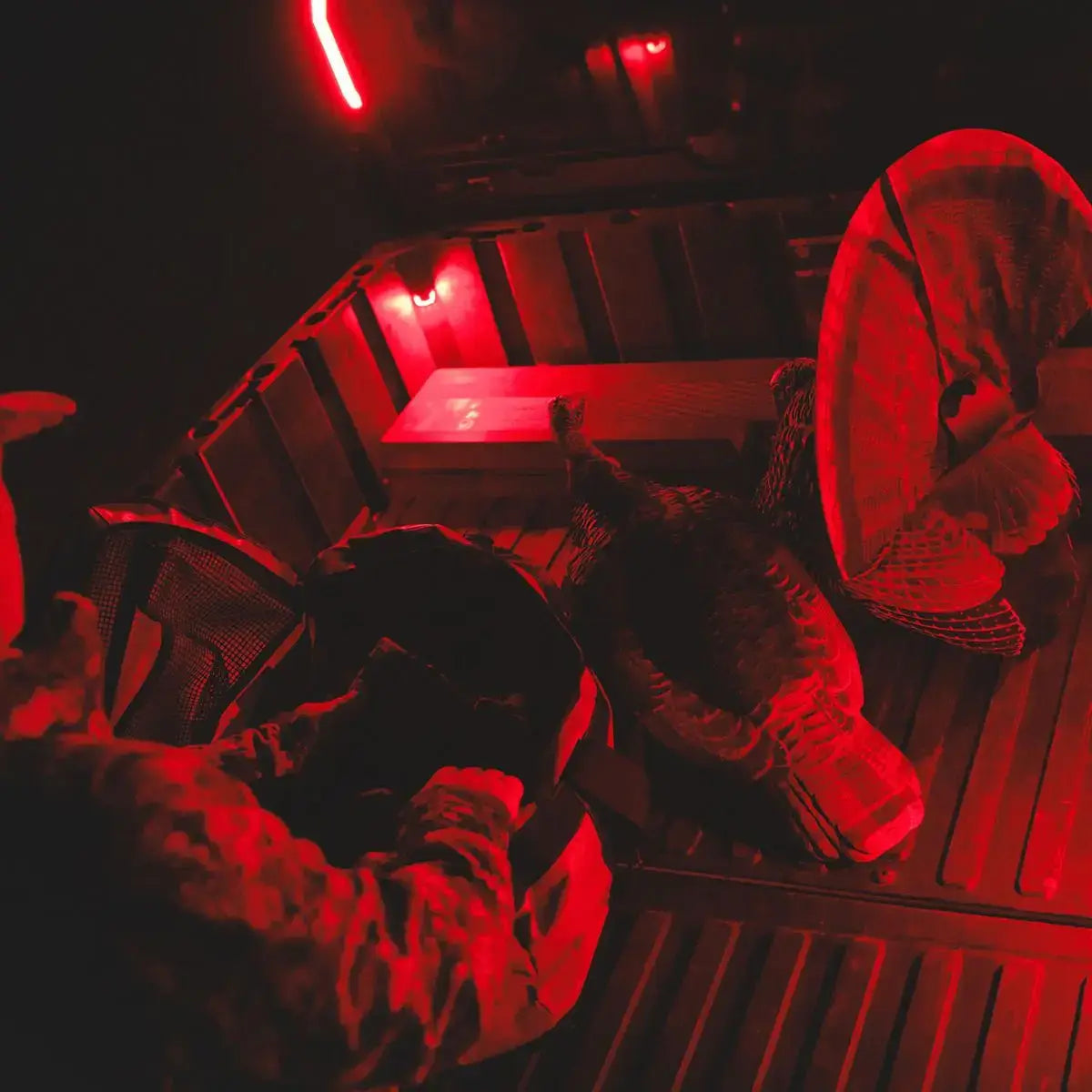 Red-tinted image of a SXS bed with hunting gear
