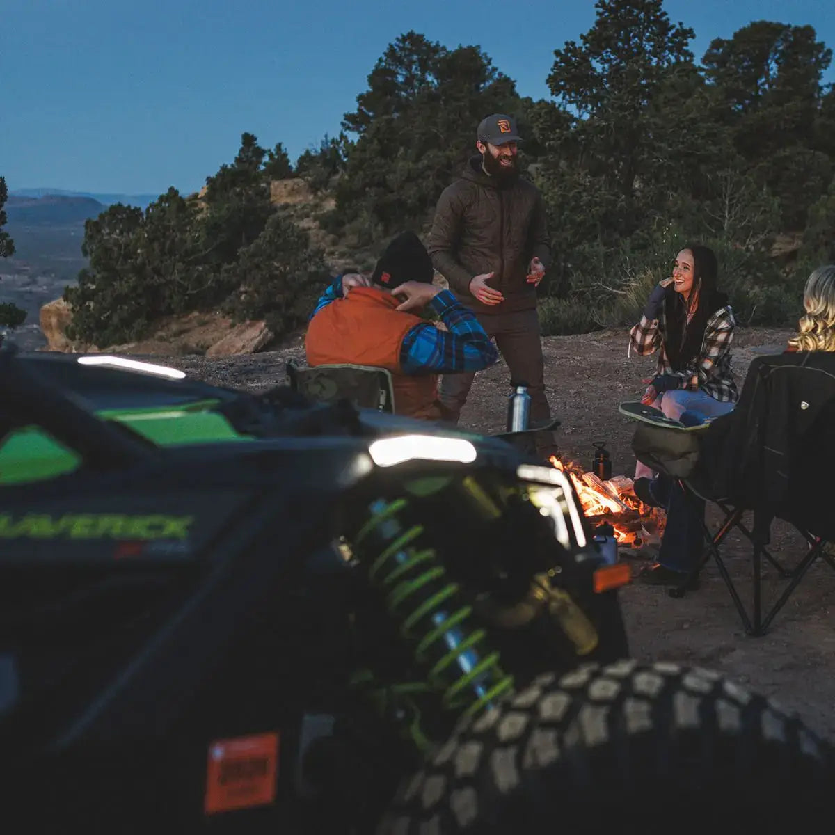 Group of people around a campfire with a vehicle in the foreground