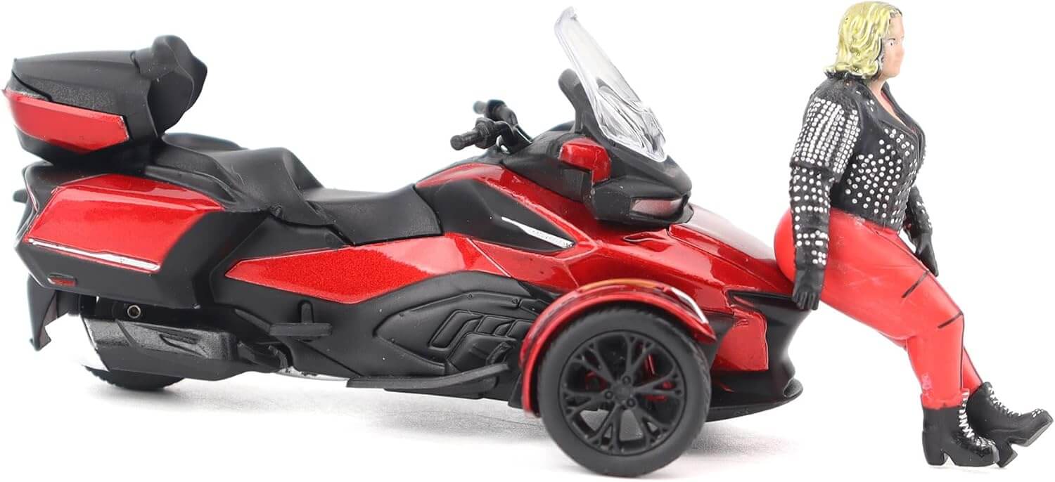 Model of a red and black three-wheeled toy vehicle with a person in a black and red outfit standing next to it on a white background.