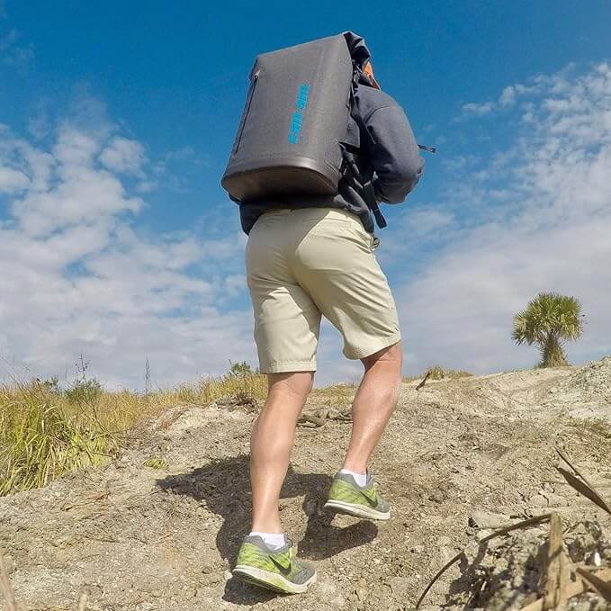Person hiking on a trail with a large backpack against a blue sky.