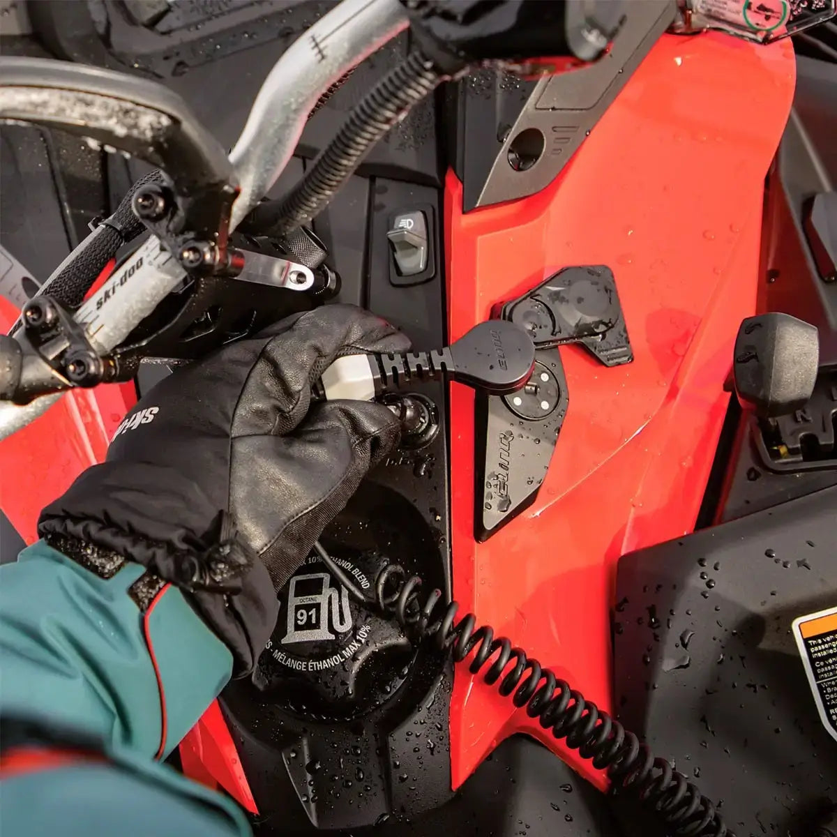 Close-up of a gloved hand adjusting a vehicle's door handle on a red vehicle.
