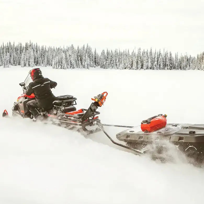 Person riding a snowmobile in a snowy landscape with trees in the background