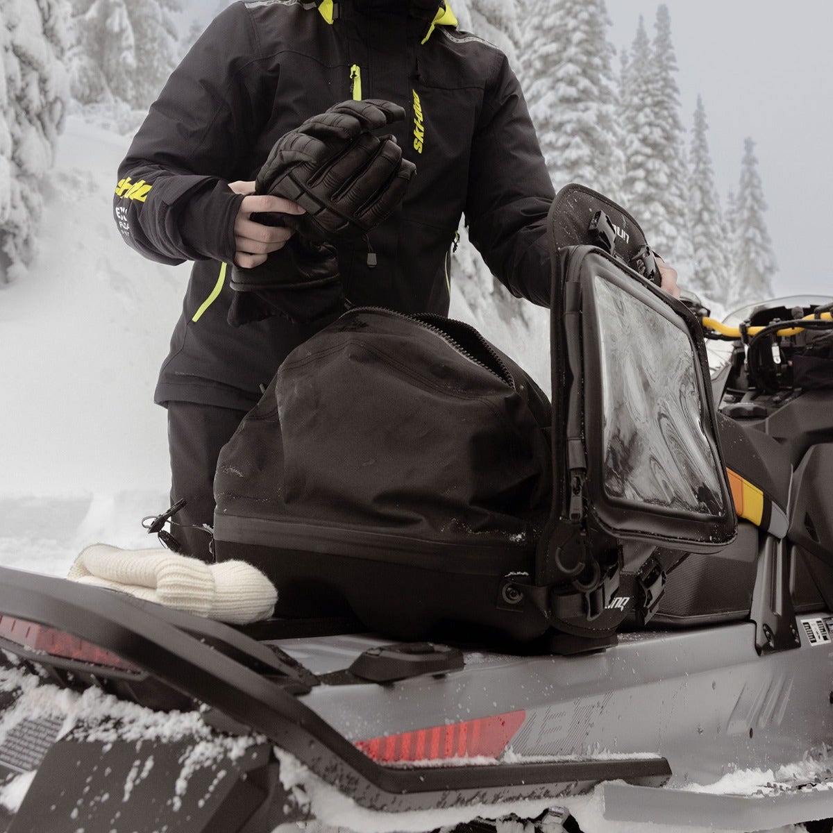 Rider opening the Ski-Doo LinQ Trail Pro Bag 860201986 on a snowmobile