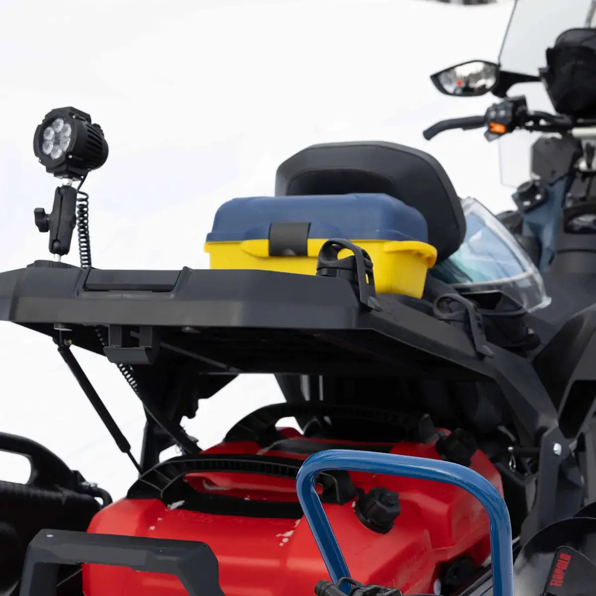 Close-up of a red ATV with a yellow storage box and black seat on a white background