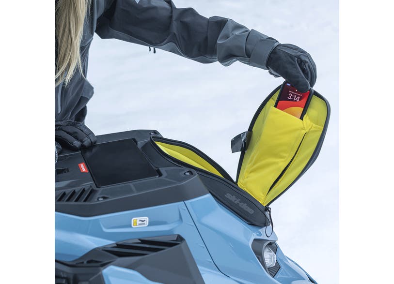 Ski-Doo black soft glove box extension mounted on snowmobile console with phone stored inside