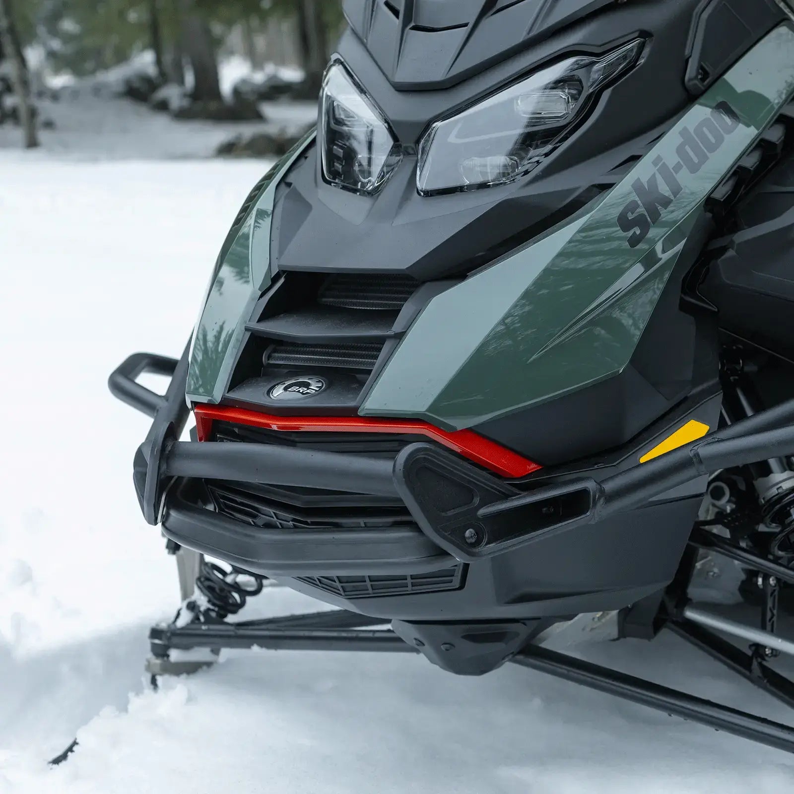 Close-up of a snowmobile in a snowy forest setting