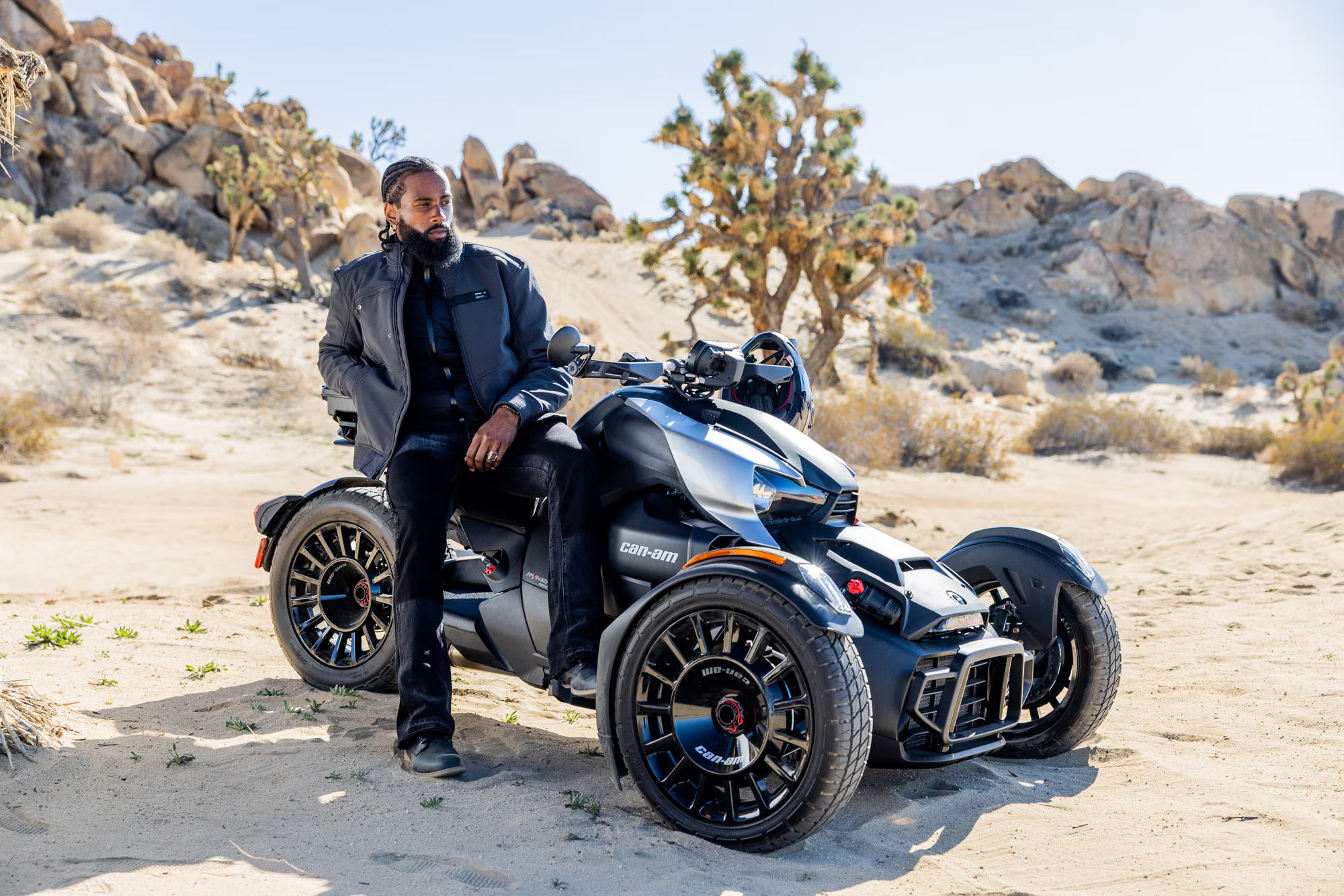 Person sitting on a black Can-Am Ryker in a desert landscape