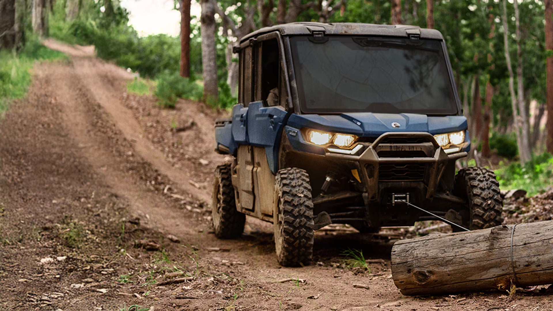 Blue off-road Can-Am vehicle on a dirt path in a forest