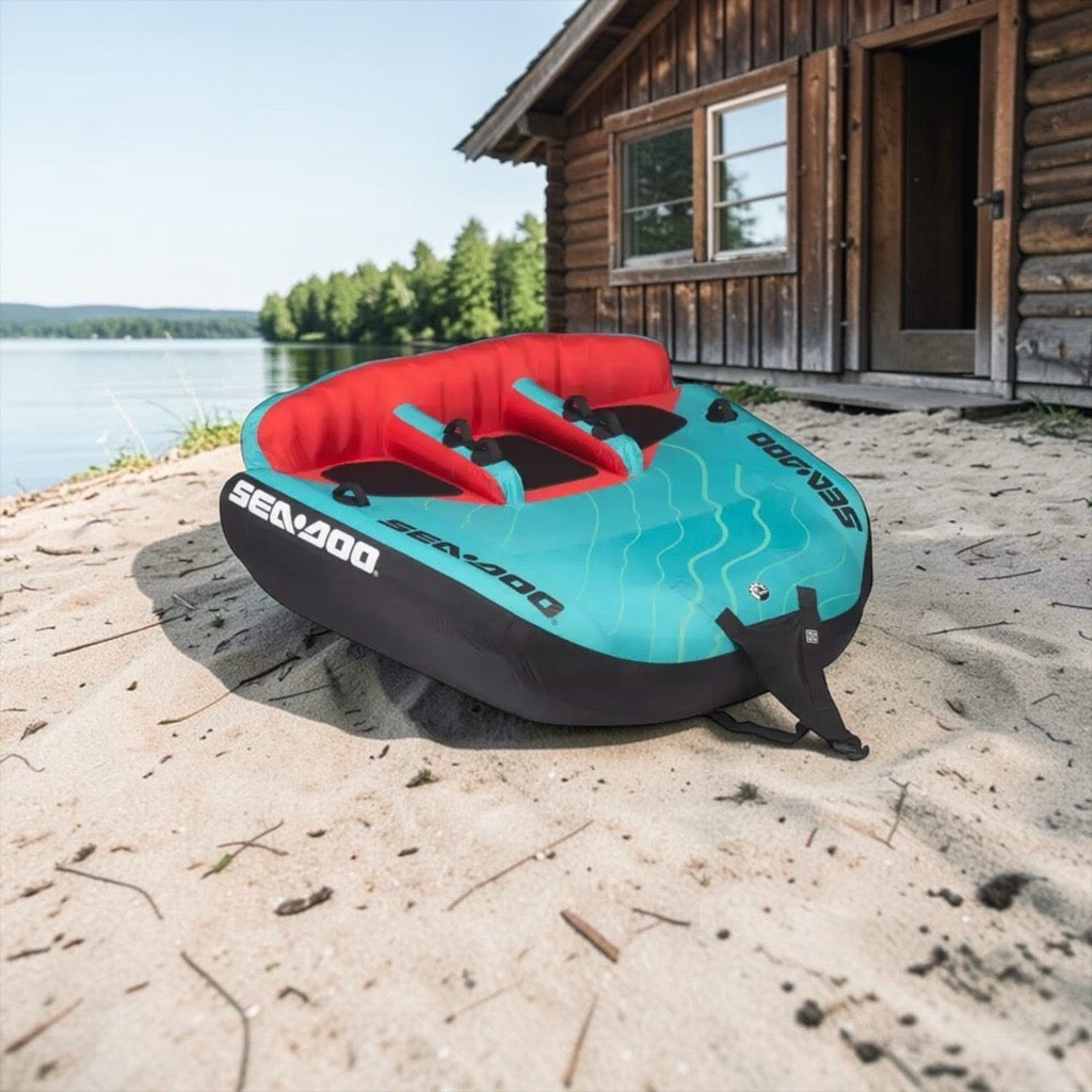 Inflatable tube with red interior on a sandy beach in front of a wooden cabin.