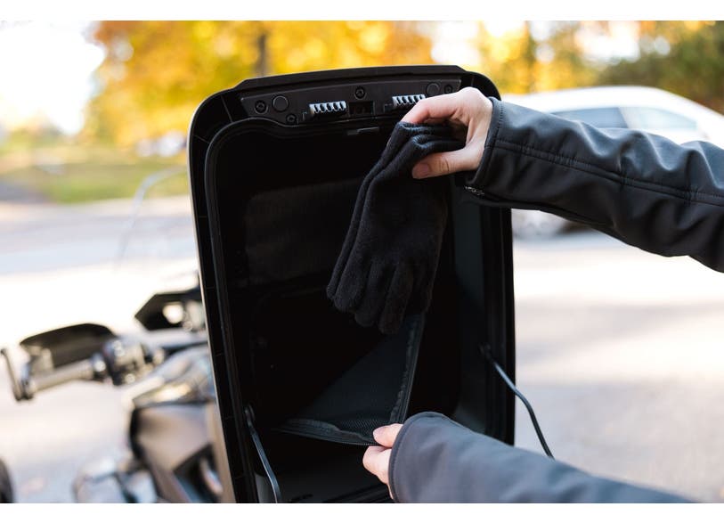 Rider placing black glove into Can-Am Ryker LinQ top case inner liner