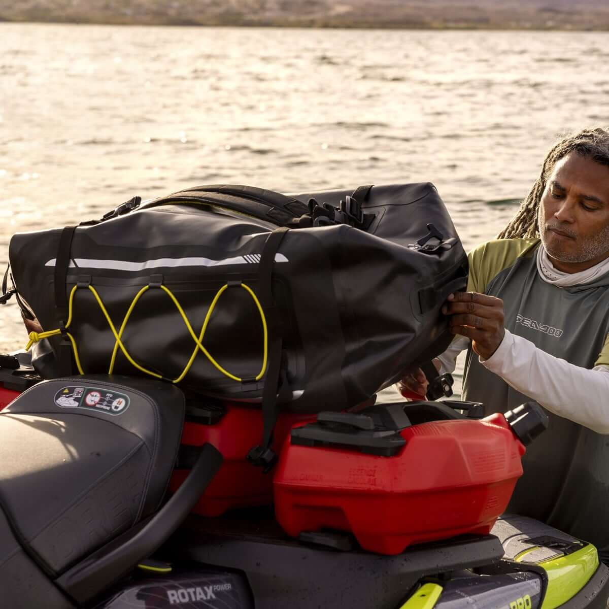 A man standing next to a Sea-Doo PWC, attaching a bag to it
