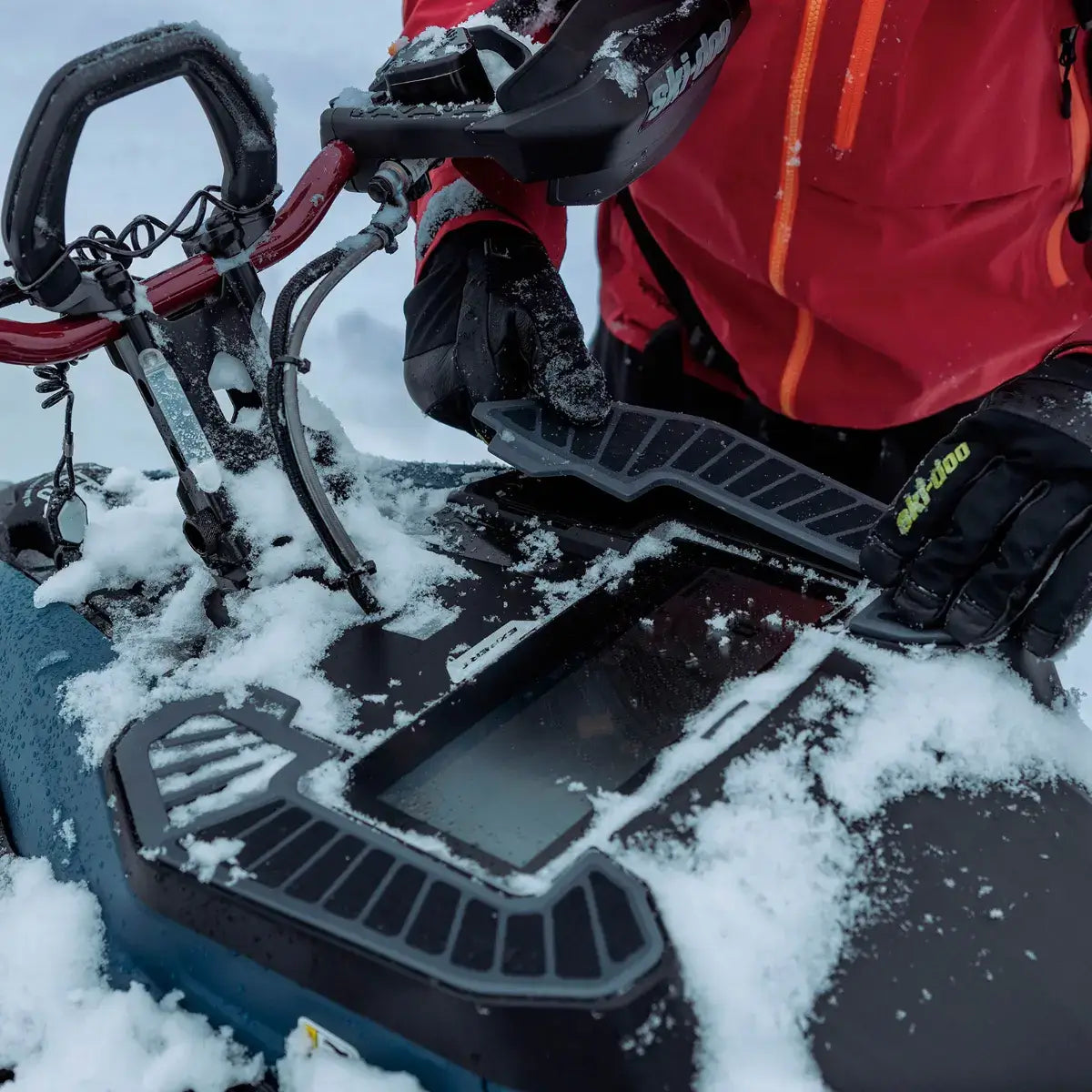 Person adjusting snowmobile tracks in a snowy environment