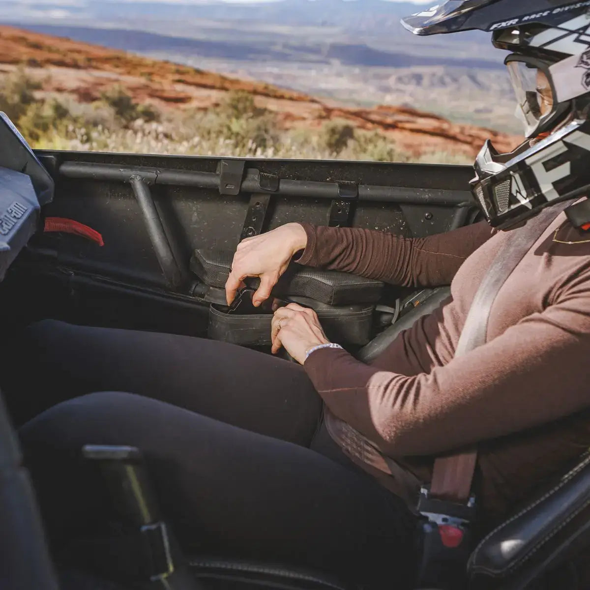 Person riding in Can-Am utv, showing off the armrest pouch